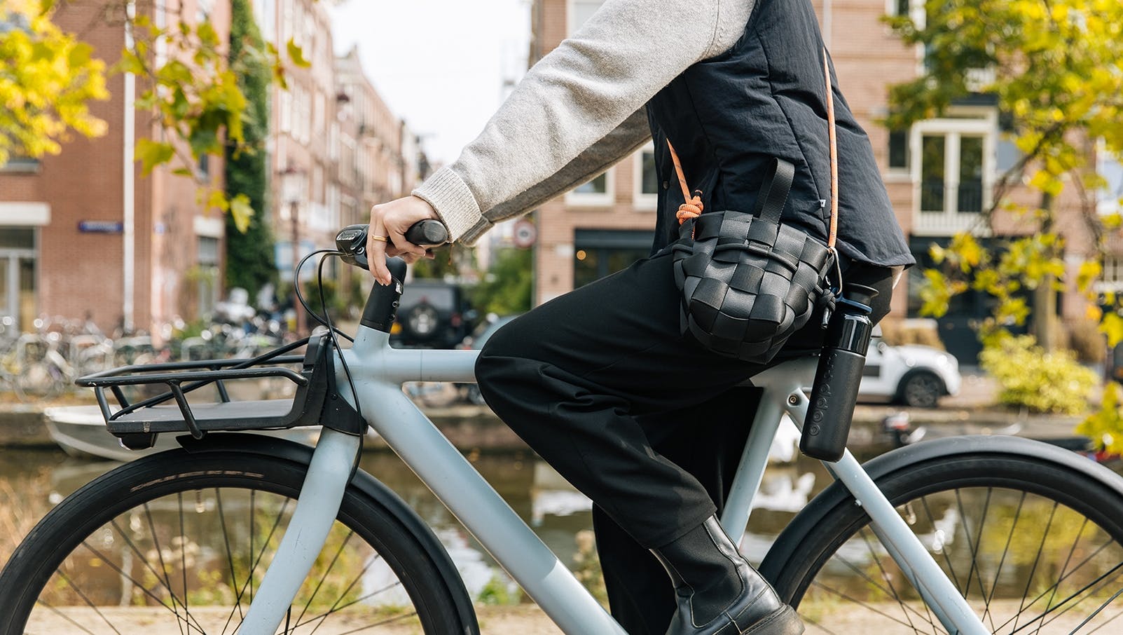 Close up from a person riding a bike and carrying a black Dopper Insulated bottle attached to her bag