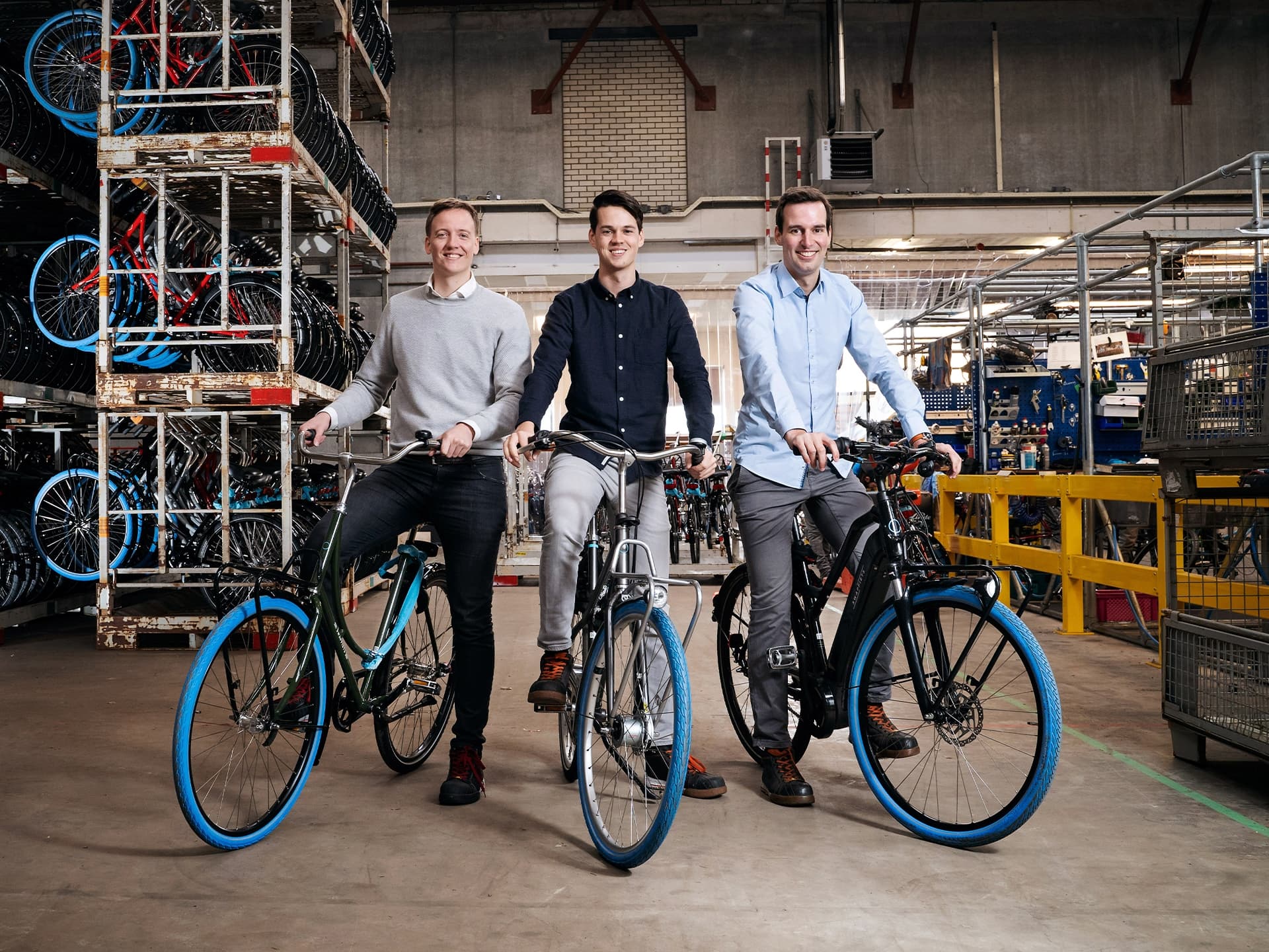 Three men on Swapfiets bikes in its garage