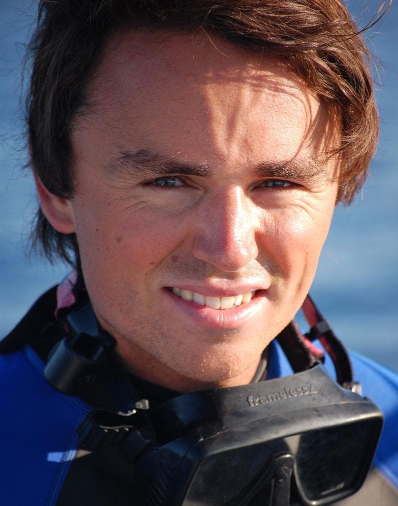 Smiling man wearing scuba gear and goggles around his neck